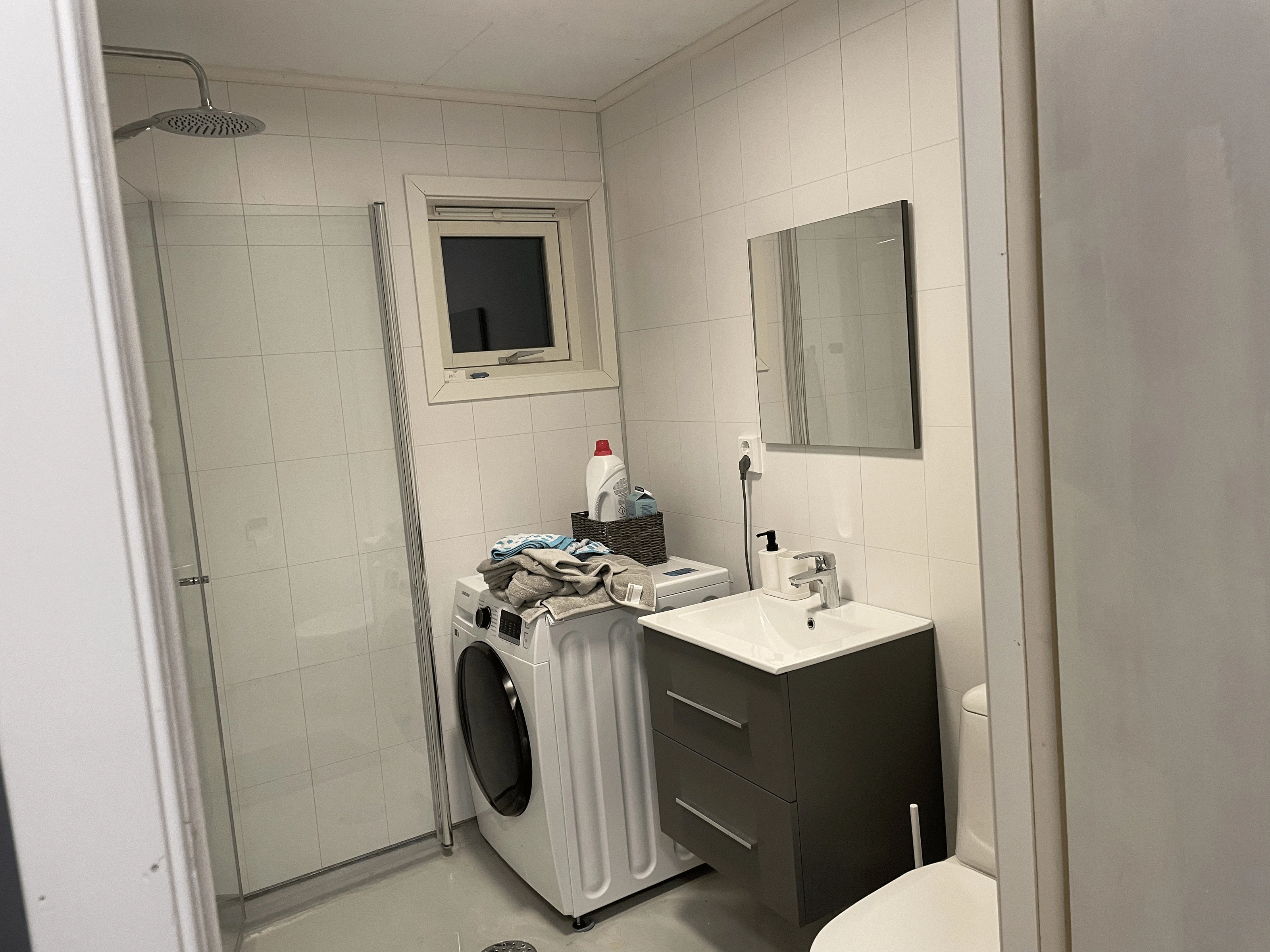 Renovated bathroom with a shower stall, washing machine, and new sink.